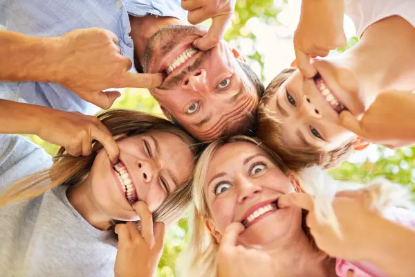 Eltern und Kinder haben Spaß zusammen beim Grimasse schneiden und Zähne zeigen